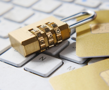 Cadenas a combinaison en laiton et carte de credit doree poses sur un clavier blanc.